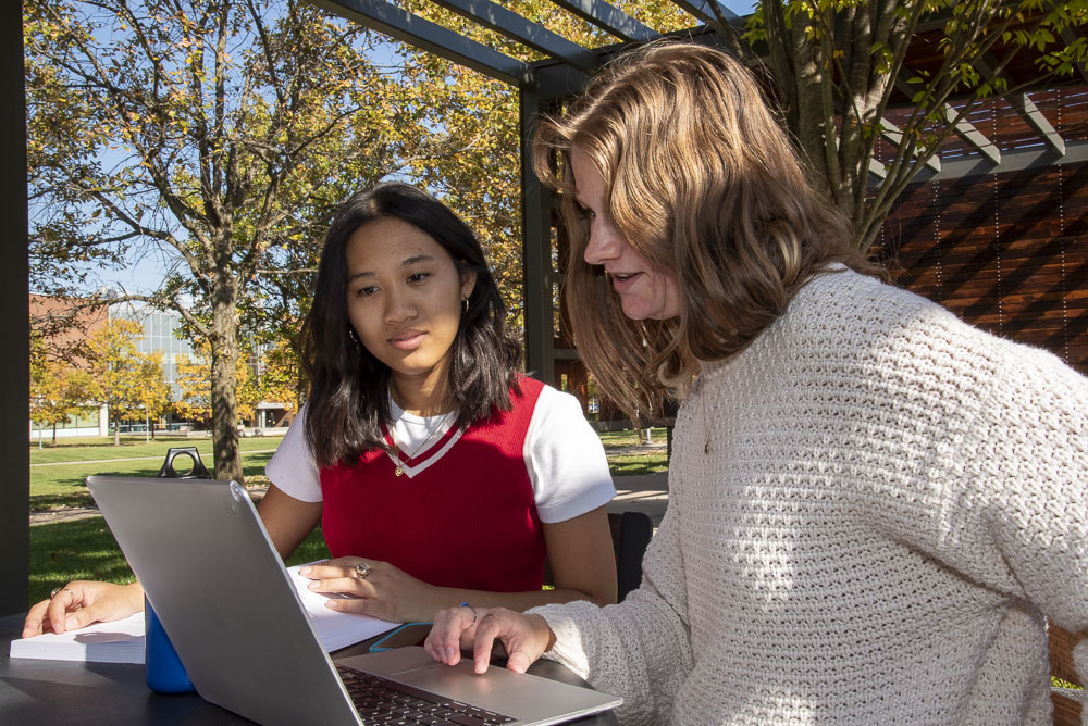 Chai Risma studying outside with a classmate