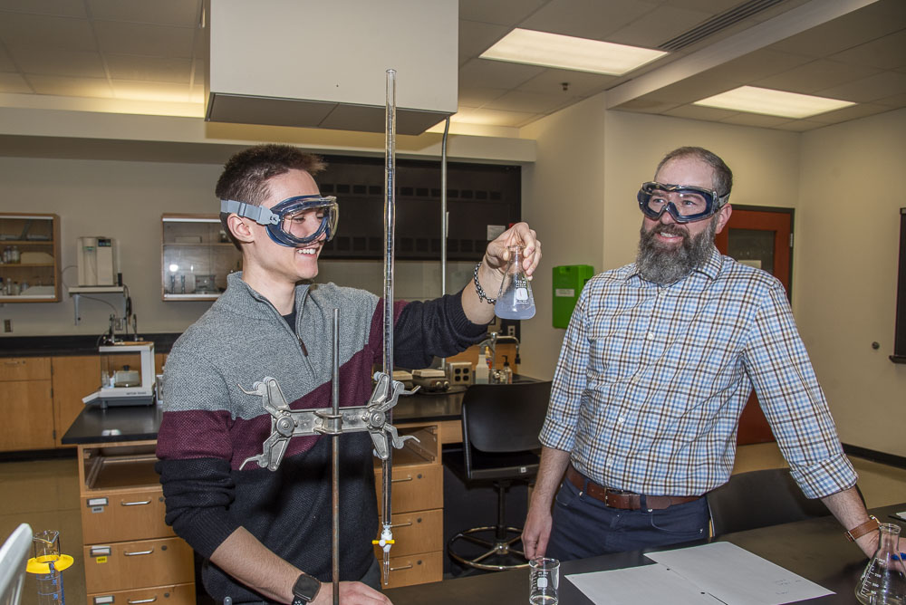 student working in chemistry lab with professor