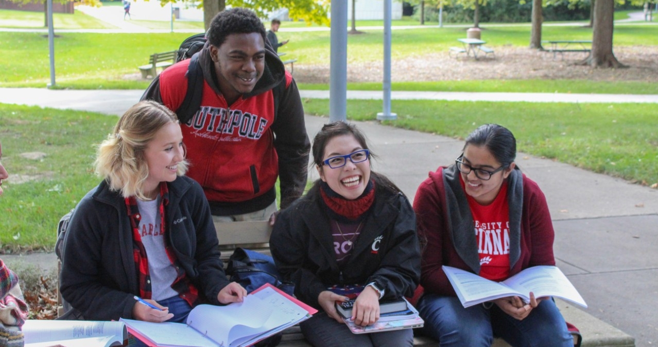 A group of students sitting on a bench at UC Blue Ash College