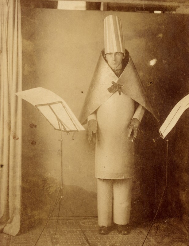 Old photo with man standing wearing a hat and cape 
