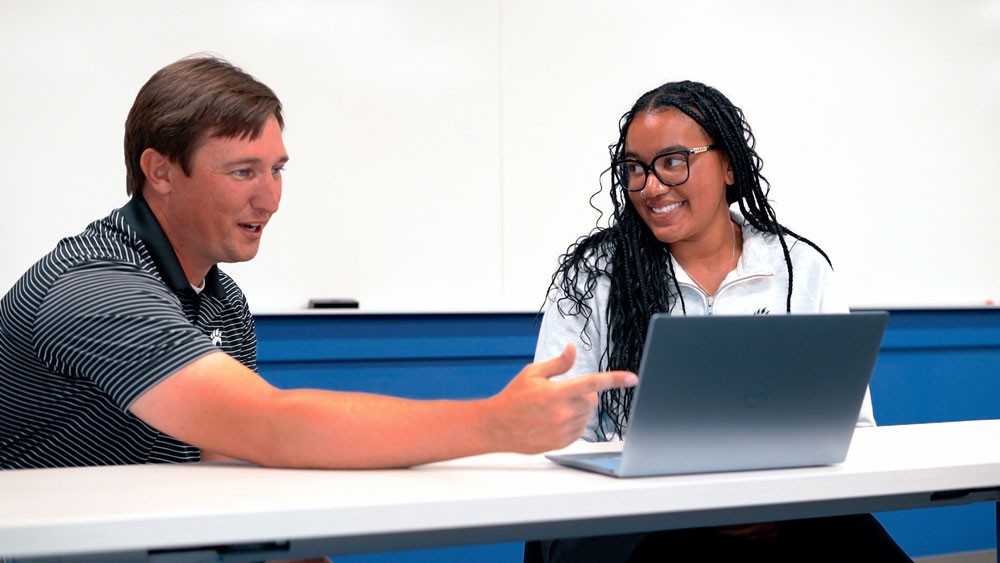 student and professor at table with laptop