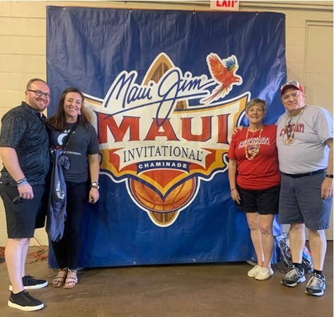 Kelsi Becker with family posing in front of Maui Invitational banner