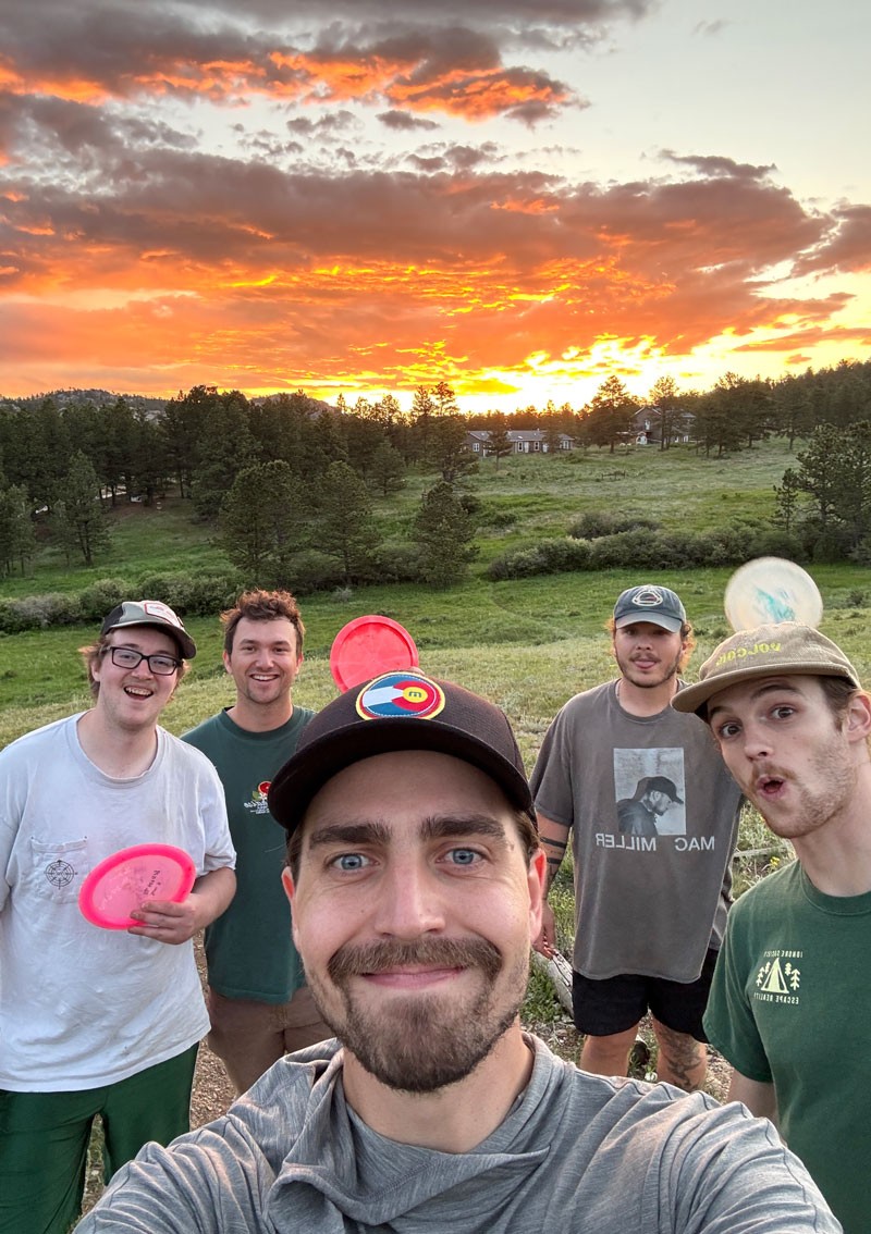 five people with frisbees and sunset