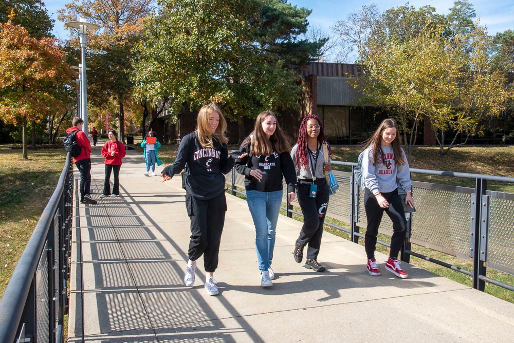 students walking across outdoor campus bridge